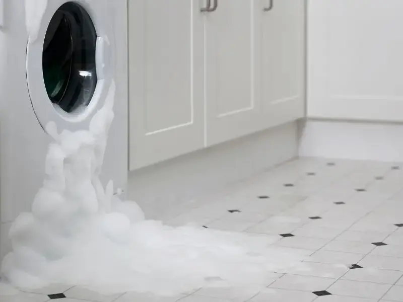 Water spreading across a floor from a failed washing machine hose