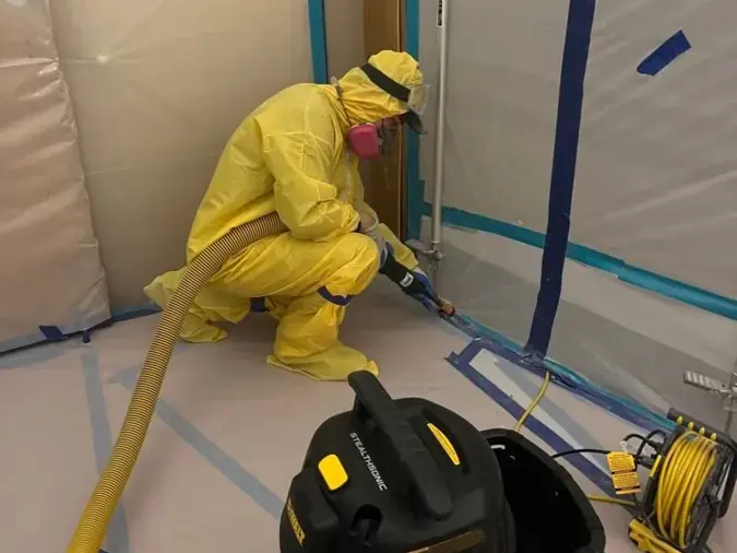 Technician in a protective suit cleaning up after a sewage backup