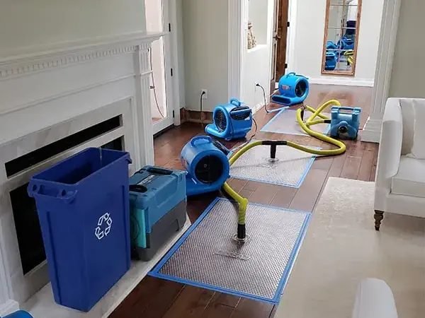 Air movers and a dehumidifier drying a room after the lower drywall was cut away